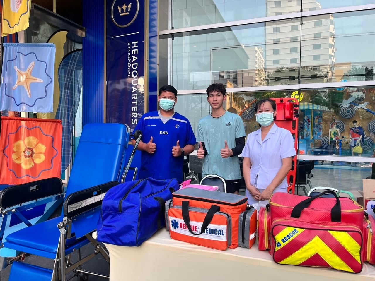 W-Asia emergency medical team standing with rescue bags beside a standby ambulance