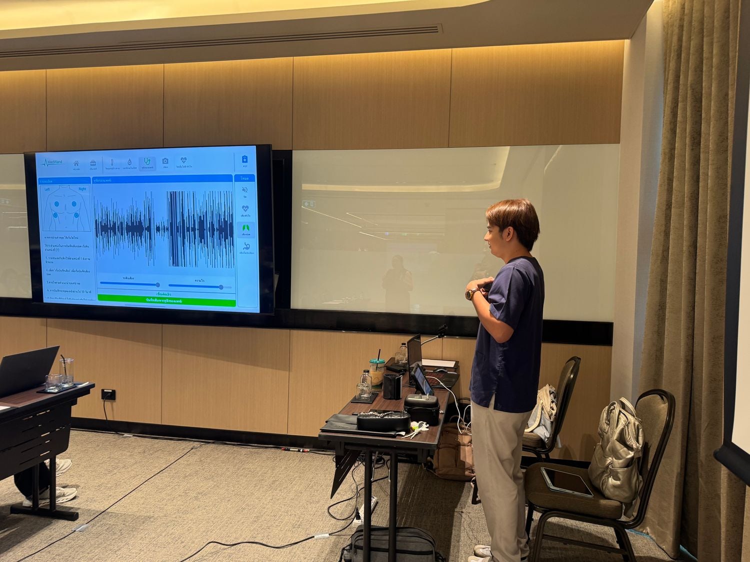 A W-Asia clinician presenting screening results on a large data display