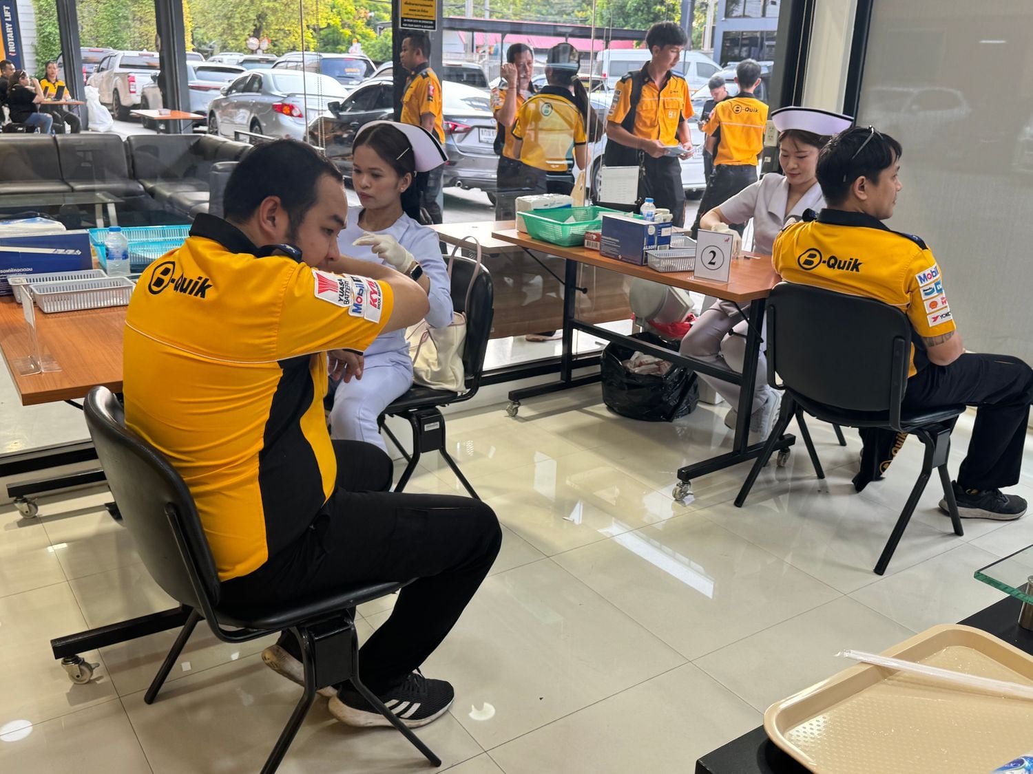 W-Asia nurses vaccinating staff at numbered stations during an on-site drive